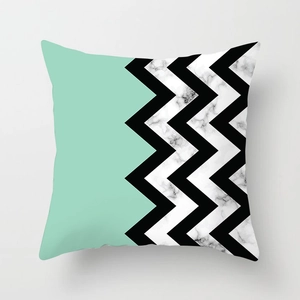 Dettaglio del motivo geometrico chevron verde menta e nero sulla federa effetto marmo