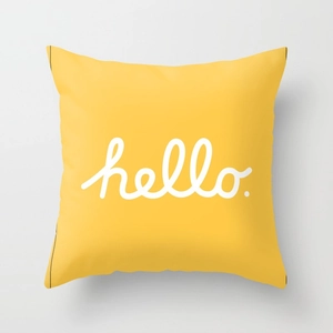 Detail of yellow pillowcase featuring white handwritten hello print on soft fabric