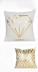 Close-up of white cushion covers with gold foil geometric leaf and diamond patterns