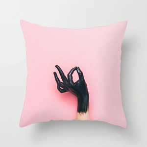 Close-up of pink decorative cushion cover featuring a black artistic hand OK sign print
