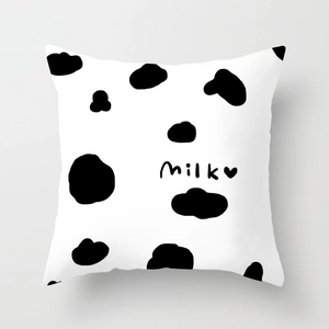 Detail of cow print throw pillow cover with milk text and heart on soft white fabric