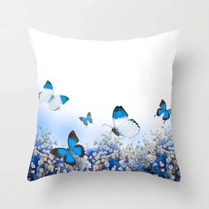 Dettaglio di farfalla blu e motivo floreale su federa per cuscino decorativo bianco