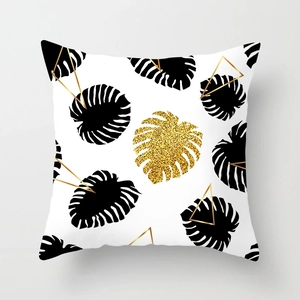 Detail showing gold foil monstera leaf and geometric triangle print on modern cushion cover