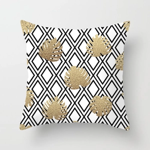 Detail of gold foil monstera leaf on black diamond pattern cushion cover with high texture