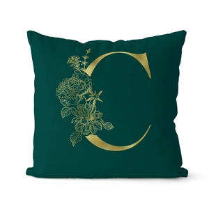 Dark green cushion cover featuring a gold letter C and floral patterns on white background