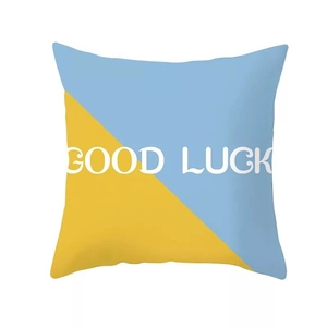 Dettaglio della federa geometrica nordica blu e gialla con scritta stampata Good Luck