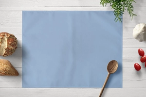 Detail of light blue linen placemat showing fabric texture with bread and wooden spoon