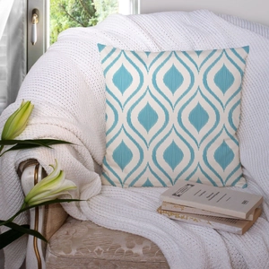 Detail of blue geometric wave pattern cushion cover on a white knit blanket