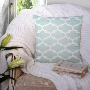 Blue and white geometric pattern square cushion cover on a cozy white knitted blanket
