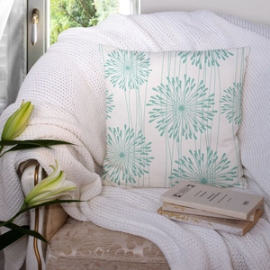 Detail of square pillowcase with teal floral pattern on a cozy white knitted blanket