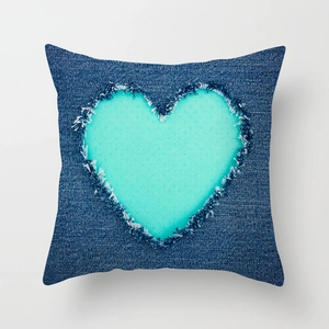 Close-up of heart-shaped cutout on teal geometric pillow cover with frayed edges texture