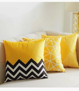 Close-up of yellow geometric pattern pillow covers on a soft fabric sofa with a warm lamp