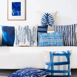 Blue geometric linen pillow covers set featuring tropical leaves and patterns on a sofa