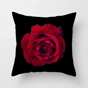 Square black pillow cover featuring a vibrant large red rose floral print on a white background