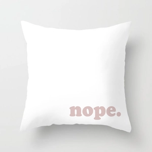 Close-up of minimalist white cushion cover with pink nope text and fabric texture