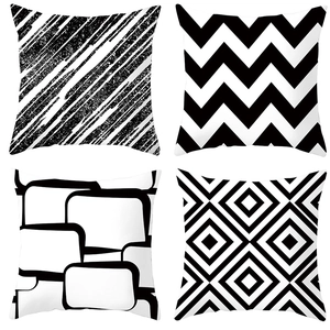 Close-up of four minimalist black and white geometric cushion covers with modern patterns