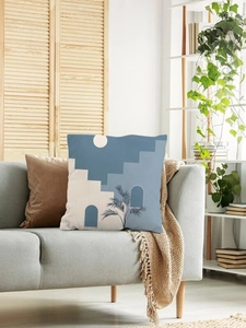 Detail view of modern abstract cushion cover with blue arch and palm leaf on sofa