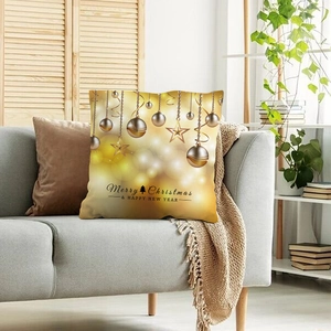 Fodera per cuscino natalizia dorata con decorazioni su divano grigio in ambiente accogliente