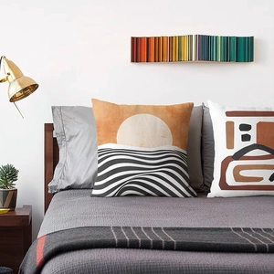 Close-up of linen cushion cover with abstract geometric orange and black wave patterns