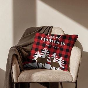 Christmas buffalo plaid pillow case with reindeer and festive greetings on an armchair