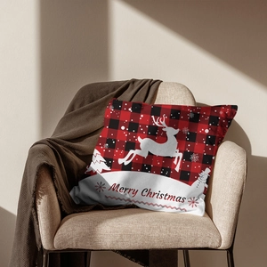 Detail of red buffalo plaid Christmas pillow with white deer silhouette on a cozy sofa
