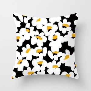 Close-up of square daisy pillow cover with bold black white floral pattern and yellow center