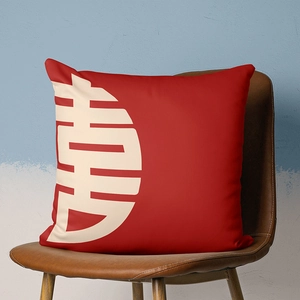 Detail of red festive cushion cover with white Xi character on a brown leather chair