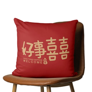 Red festive cushion cover with gold Good Thing Happens text on a brown leather chair