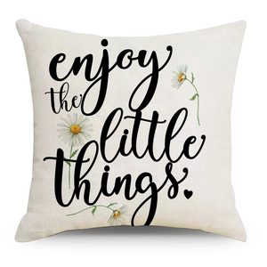 Detail of linen pillowcase with daisy print and 'enjoy the little things' quote text