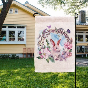 Close-up of Easter garden flag with pink bunny and floral print on grass lawn