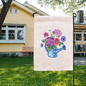 Detail of linen garden flag with floral watering can pattern in outdoor yard setting