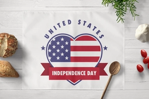 Detalle del mantel individual Independence Day con corazón bandera USA en madera blanca