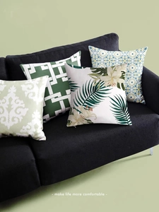 Macro shot of assorted pillow covers with green floral and geometric patterns on a sofa