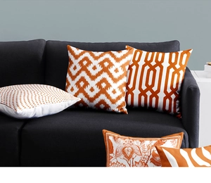 Close-up of decorative orange and white cushion covers with geometric patterns on a sofa