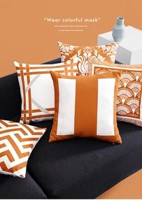 Detail of luxury orange and white throw pillows with geometric patterns on a sofa