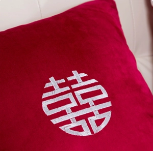 Coussin de mariage en velours rouge avec broderie Double Bonheur sur canapé blanc