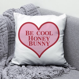 Detail of white peach skin pillow with 'BE COOL HONEY BUNNY' print on a grey sofa