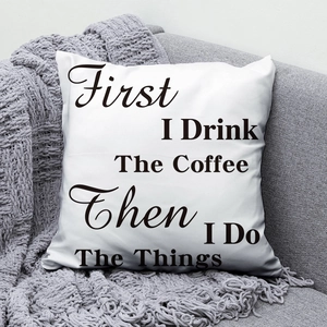 Close-up of modern white cushion with black coffee quote text on a gray sofa