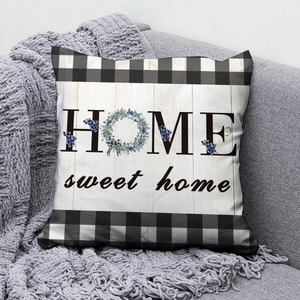 Detail of HOME sweet home printed cushion with blue berry wreath on a grey sofa