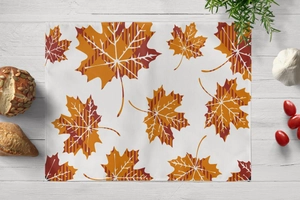 Detail view of cotton linen placemat with autumn maple leaf pattern on wood table