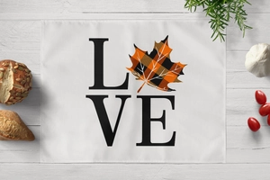 Detail of harvest-themed placemat with LOVE text and orange plaid maple leaf design