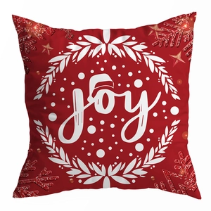 Detail eines roten Weihnachtskissenbezugs mit Joy-Schriftzug, Nikolausmütze und Schneeflocken