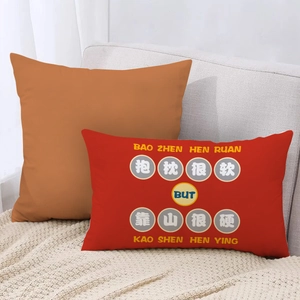 Detail view of red and orange lumbar pillows with lucky Chinese text on a sofa