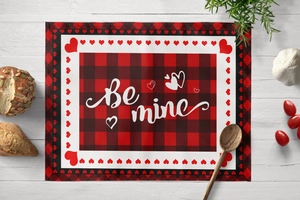 Vue à plat d'un set de table de la Saint-Valentin à carreaux avec texte Be Mine sur bois blanc