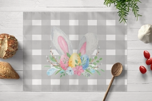 Detailansicht eines Osterhasen-Platzsets mit bunten Eiern auf weißem Holztisch