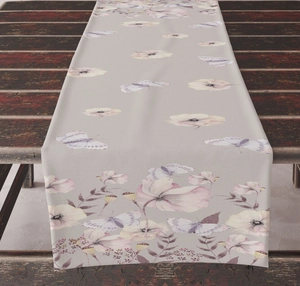 Detail of floral and butterfly print linen table runner on dark wood surface