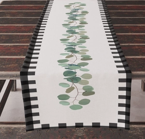 Detailed close-up of linen table runner with green eucalyptus leaves and gingham borders