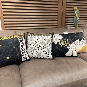 Black and white floral cushion covers with motivational quotes on a leather sofa