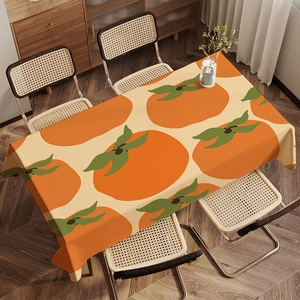 Close-up of thick fabric tablecloth featuring orange persimmon and green leaf patterns