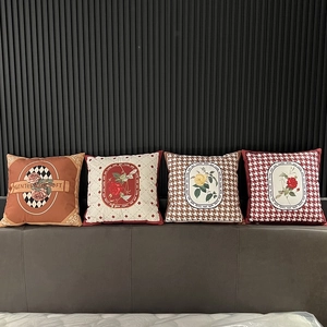 Detail of four geometric and floral pattern cushion covers on a gray headboard